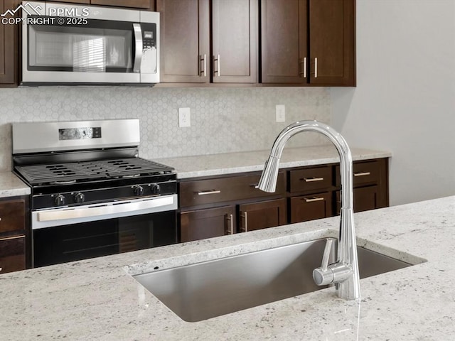 kitchen with dark brown cabinets, a sink, and appliances with stainless steel finishes