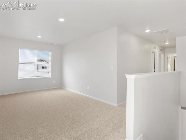 carpeted empty room featuring baseboards, visible vents, and recessed lighting
