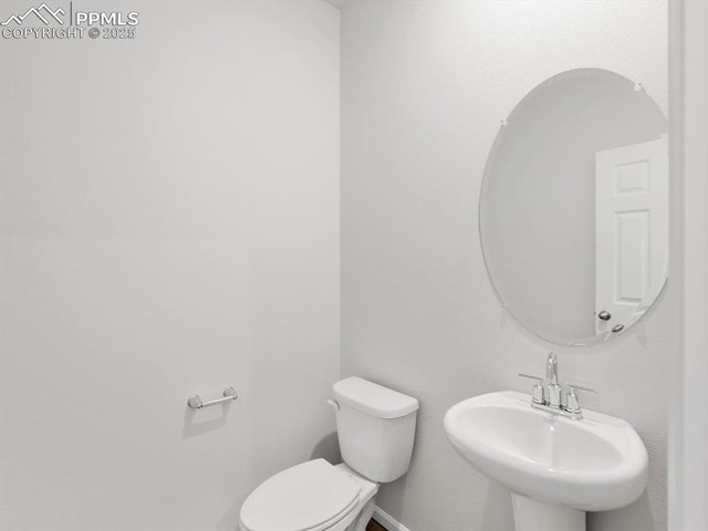 bathroom featuring baseboards, a sink, and toilet