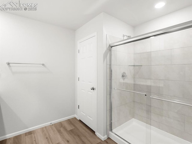 bathroom with recessed lighting, a shower stall, wood finished floors, and baseboards