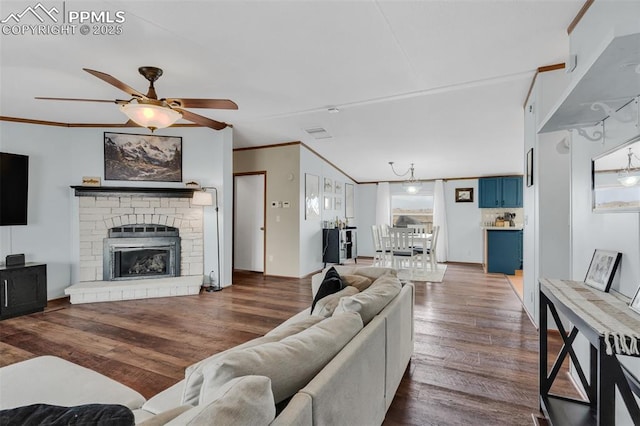 living room featuring ornamental molding, a glass covered fireplace, dark wood finished floors, and a ceiling fan