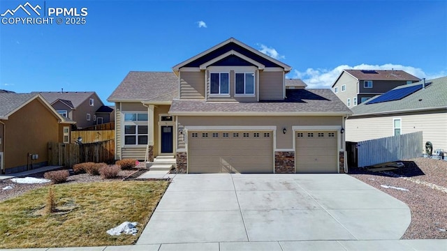 view of front of home featuring stone siding, a residential view, fence, and concrete driveway