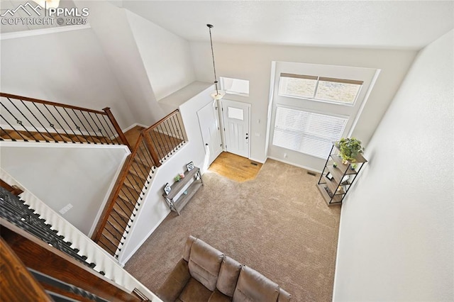 foyer featuring carpet, visible vents, high vaulted ceiling, baseboards, and stairs