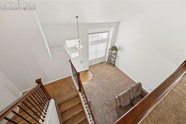 stairway featuring vaulted ceiling, carpet, and baseboards