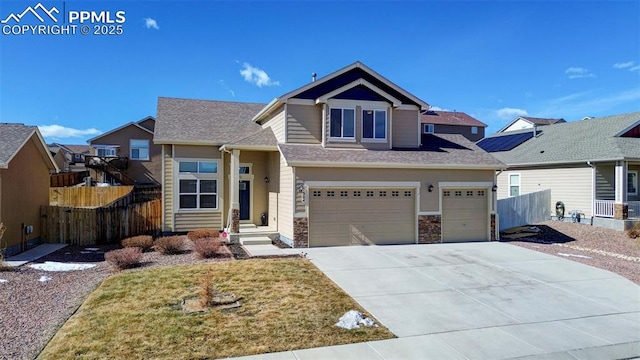 view of front of home with a garage, driveway, stone siding, and fence