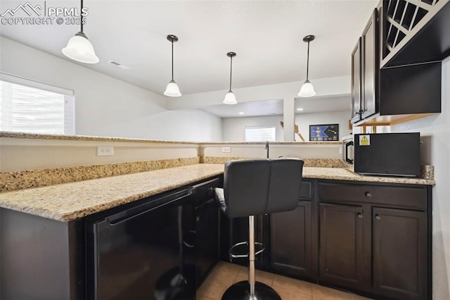 kitchen featuring light stone countertops, pendant lighting, dark brown cabinetry, and light tile patterned floors