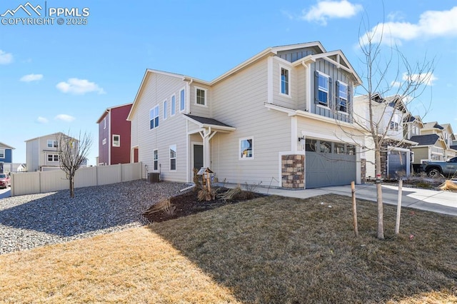 craftsman inspired home with concrete driveway, an attached garage, board and batten siding, fence, and a residential view