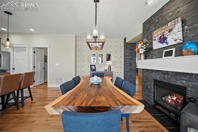 dining room featuring visible vents, a fireplace, baseboards, and wood finished floors