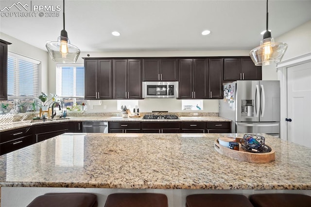 kitchen with a sink, stainless steel appliances, a kitchen breakfast bar, and a center island