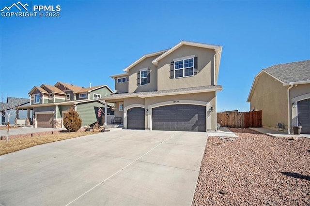 traditional-style house with stucco siding, fence, a residential view, concrete driveway, and an attached garage