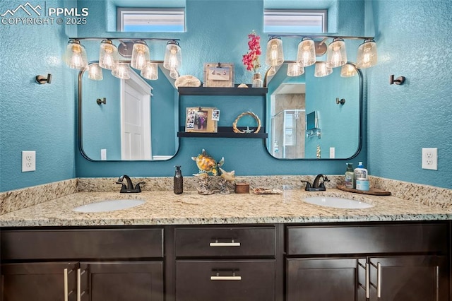 full bathroom with double vanity, a textured wall, and a sink