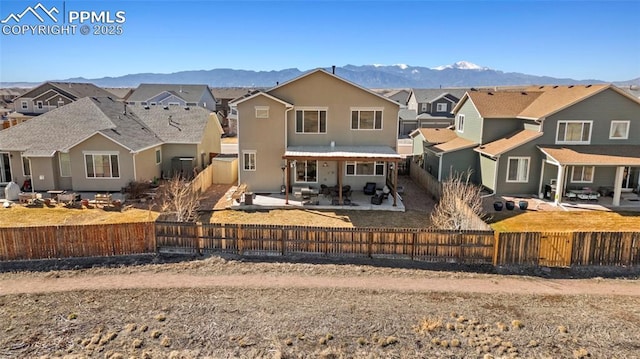 back of property featuring a patio area, a residential view, a mountain view, and a fenced backyard