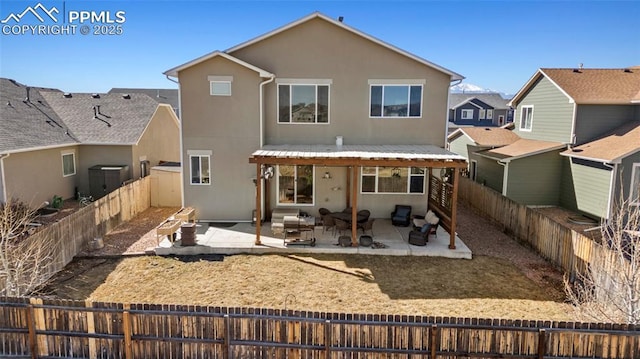 rear view of house with stucco siding, a patio, and a fenced backyard