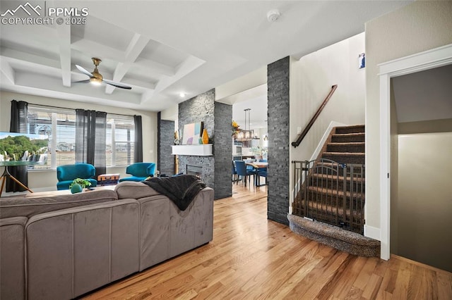 living area with stairway, a fireplace, light wood-type flooring, and coffered ceiling