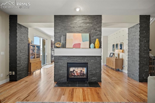 living room with baseboards, a multi sided fireplace, and wood finished floors