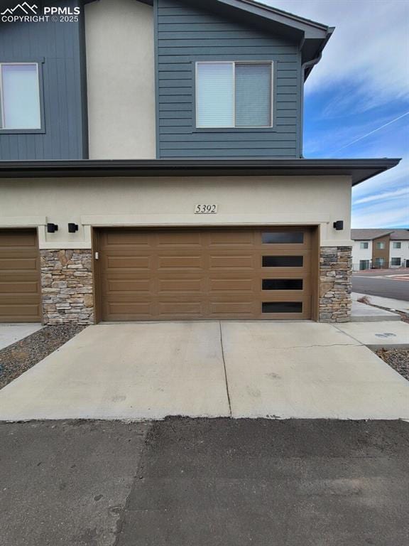 view of front facade with stone siding, driveway, and an attached garage