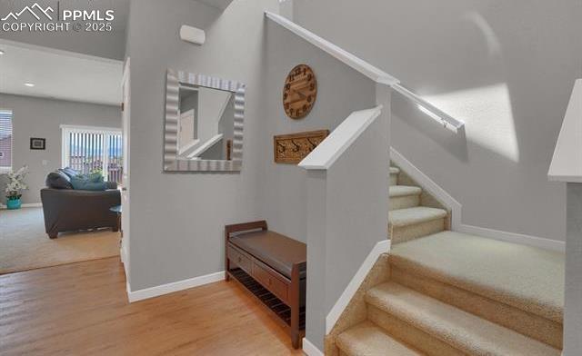 stairs featuring carpet flooring, wood finished floors, and baseboards