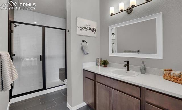 bathroom with tile patterned floors, vanity, a shower stall, and toilet