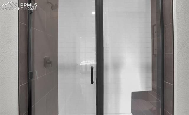 bathroom with a stall shower and a textured wall