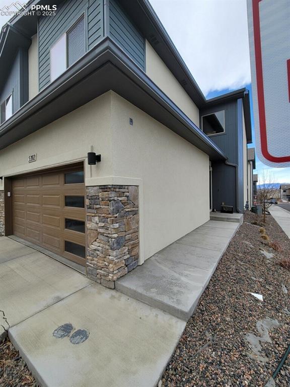 view of home's exterior with a garage, stone siding, and stucco siding