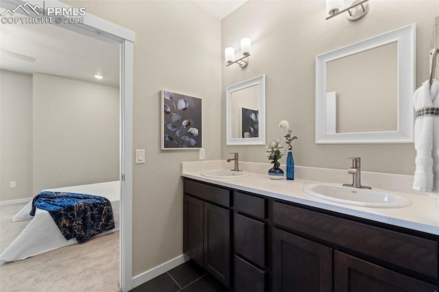 bathroom with a sink, baseboards, double vanity, and ensuite bathroom