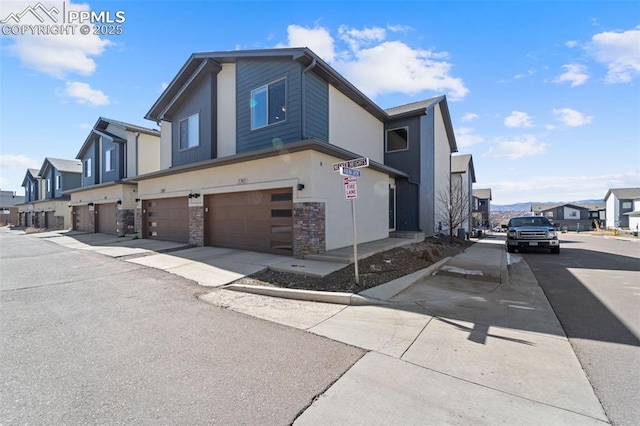 view of front of house with a residential view, stucco siding, a garage, and stone siding