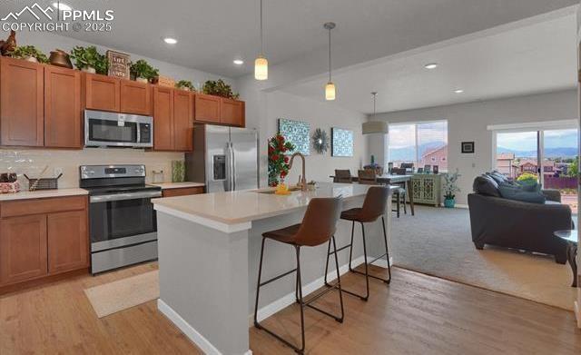 kitchen with brown cabinets, appliances with stainless steel finishes, light countertops, and a sink