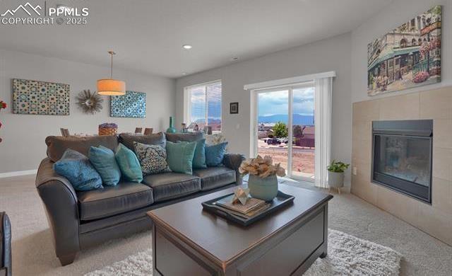 living room featuring a tiled fireplace, recessed lighting, and light colored carpet