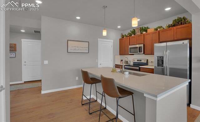 kitchen featuring a sink, brown cabinets, light wood finished floors, and stainless steel appliances