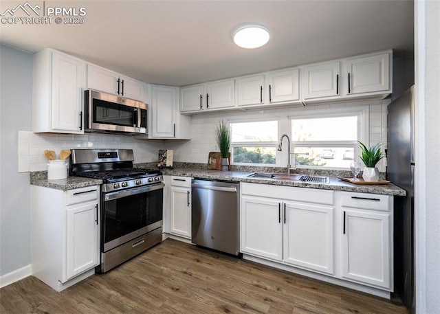 kitchen featuring tasteful backsplash, appliances with stainless steel finishes, white cabinets, and a sink