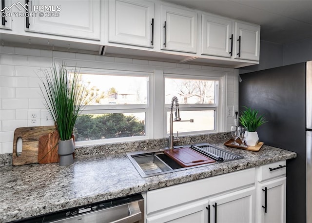 kitchen featuring a sink, tasteful backsplash, white cabinets, and dishwasher