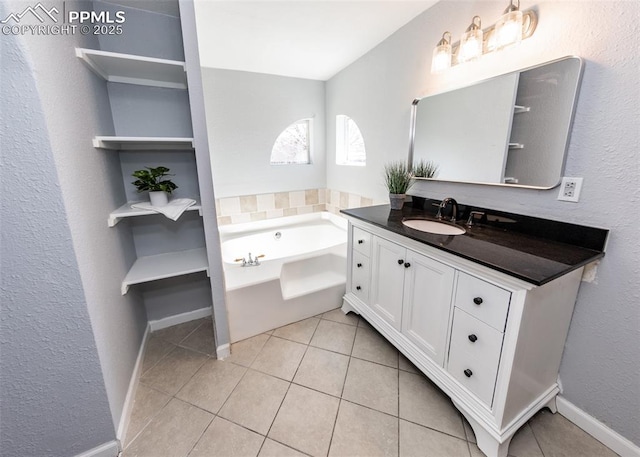 bathroom featuring a garden tub, vanity, baseboards, and tile patterned floors