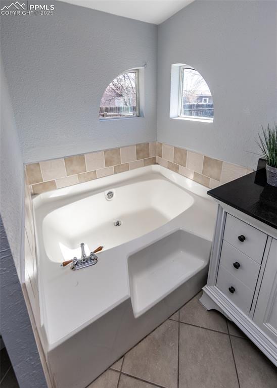 full bath with a garden tub and tile patterned floors