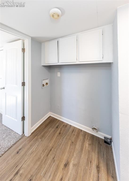 laundry area featuring washer hookup, cabinet space, baseboards, and wood finished floors