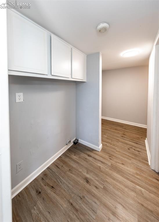 laundry area with light wood-style floors and baseboards