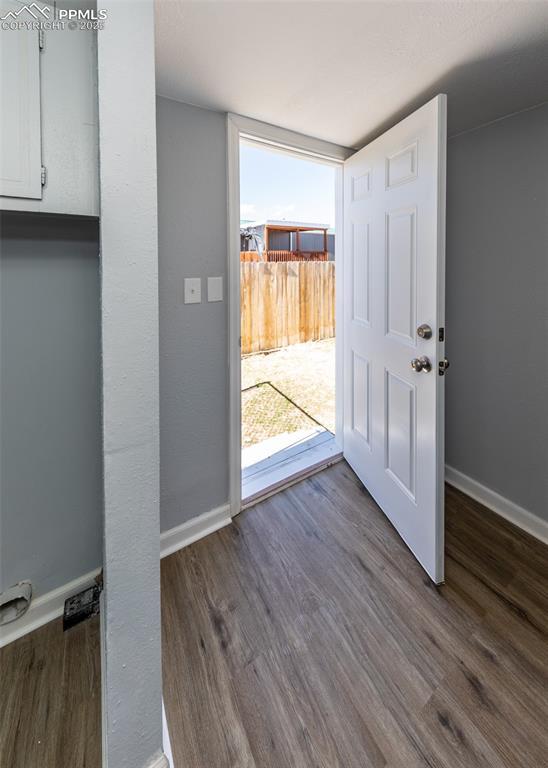 entryway with dark wood-type flooring and baseboards