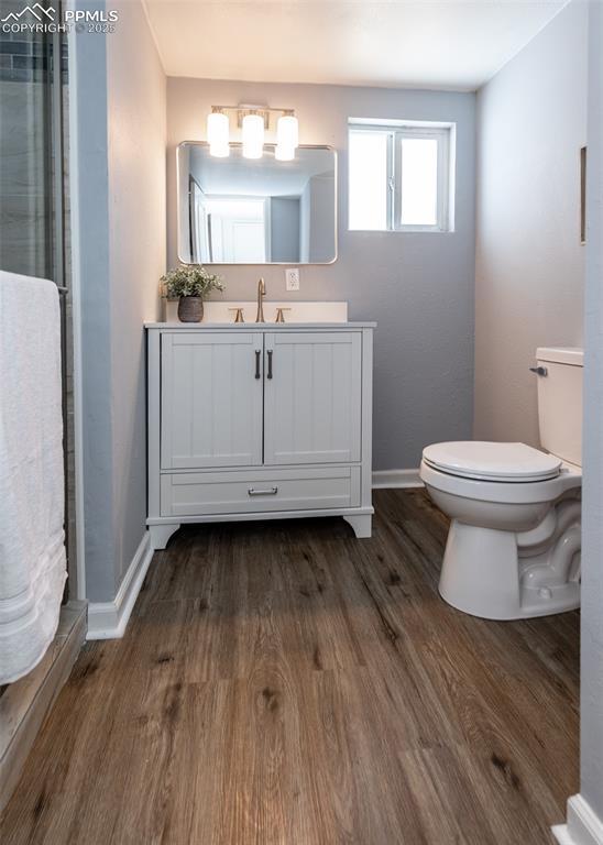 bathroom featuring wood finished floors, toilet, and baseboards