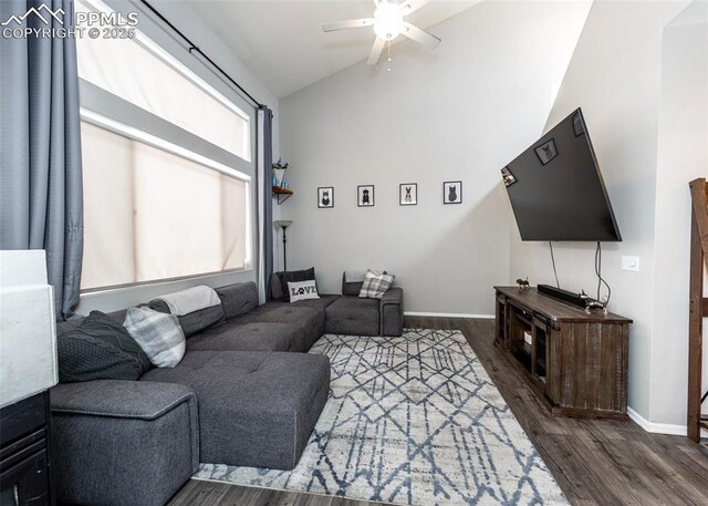 living room featuring lofted ceiling, dark wood-type flooring, a ceiling fan, and baseboards
