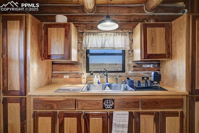 kitchen with brown cabinetry, hanging light fixtures, log walls, light countertops, and a sink