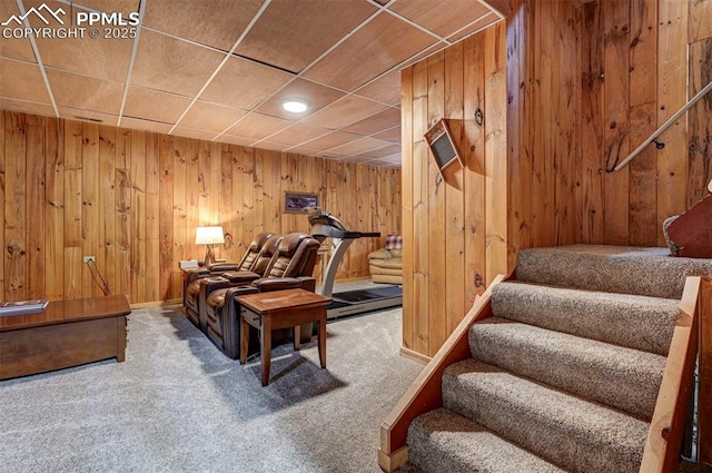 sitting room featuring wooden walls, carpet, stairs, and baseboards