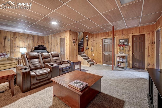 carpeted living area featuring wood walls and stairway