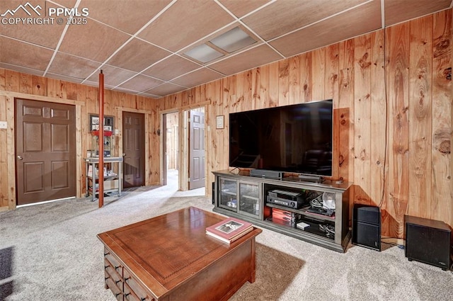 living room featuring carpet floors, a paneled ceiling, and wooden walls