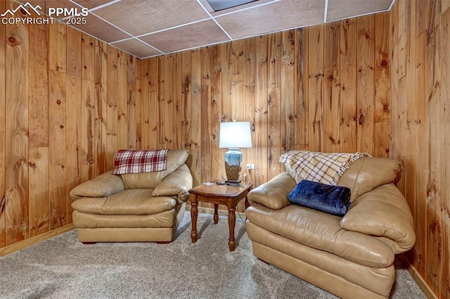 sitting room featuring carpet floors and wooden walls