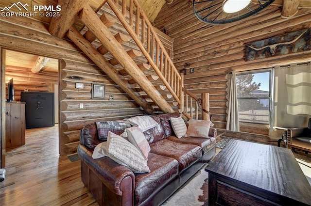 living area with lofted ceiling, stairway, and wood finished floors