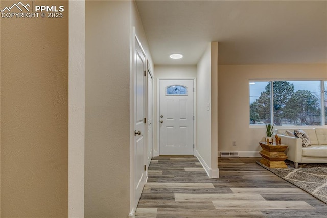 foyer featuring visible vents, baseboards, and wood finished floors