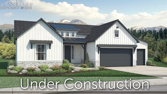 modern farmhouse style home with driveway, stone siding, a mountain view, and a standing seam roof