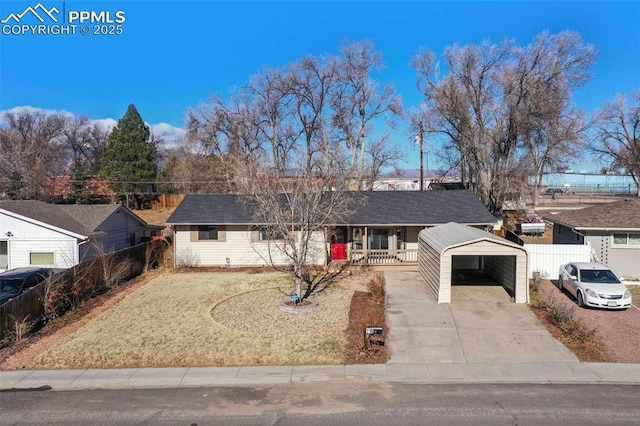 ranch-style home with a carport, covered porch, fence, and concrete driveway