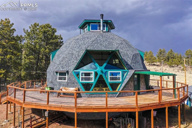 back of property featuring a shingled roof and a wooden deck