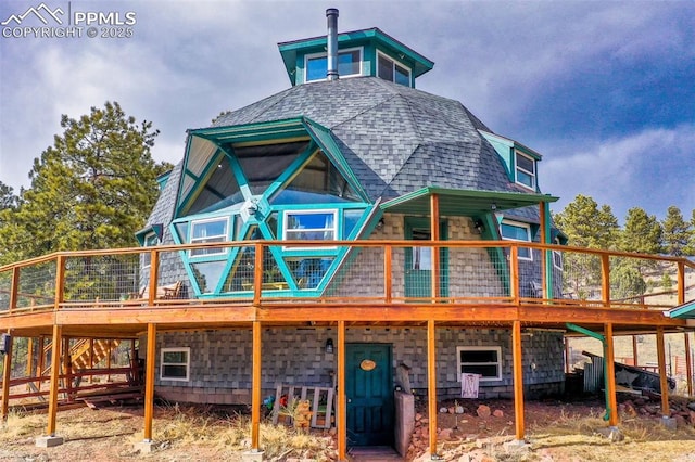 rear view of property with roof with shingles and a deck