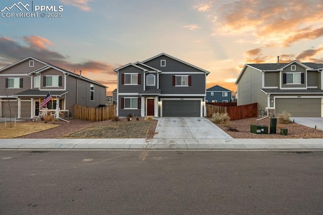 traditional home featuring a garage, concrete driveway, and fence